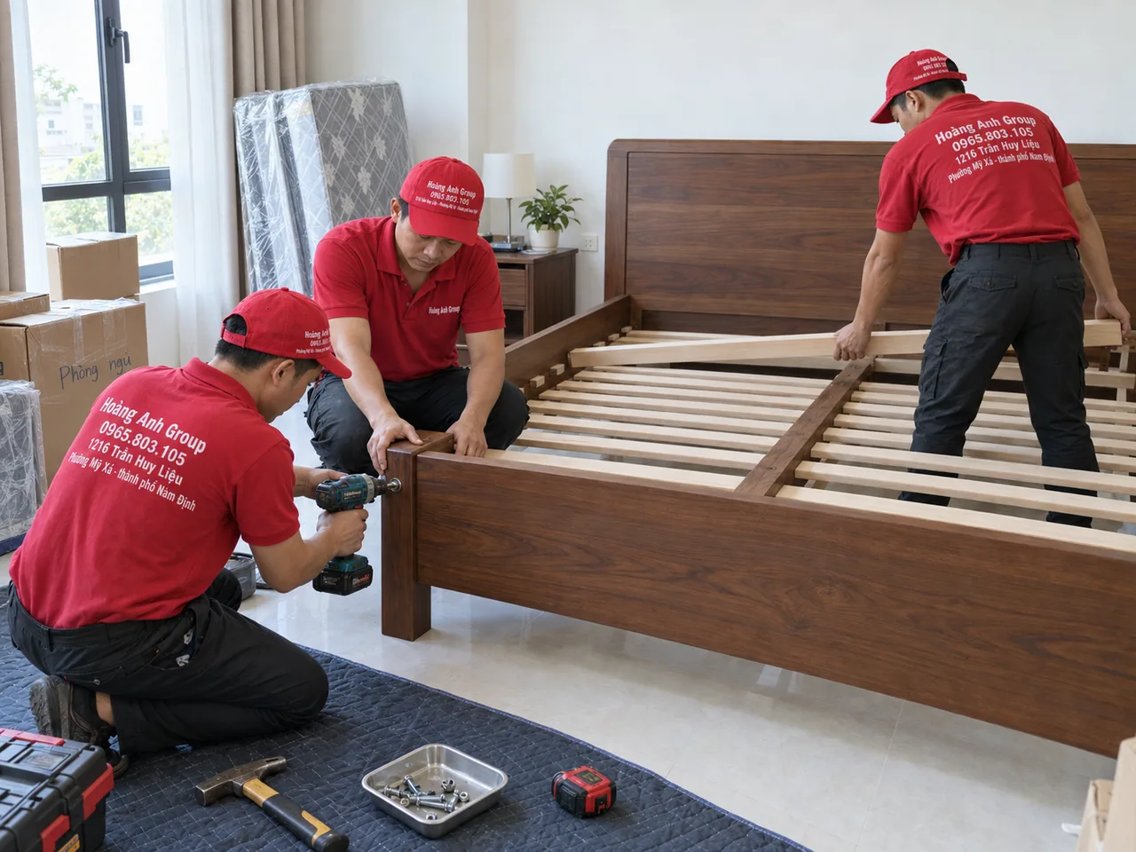 Nhân công Hoàng Anh Group phối hợp lắp khung giường gỗ trong phòng ngủ