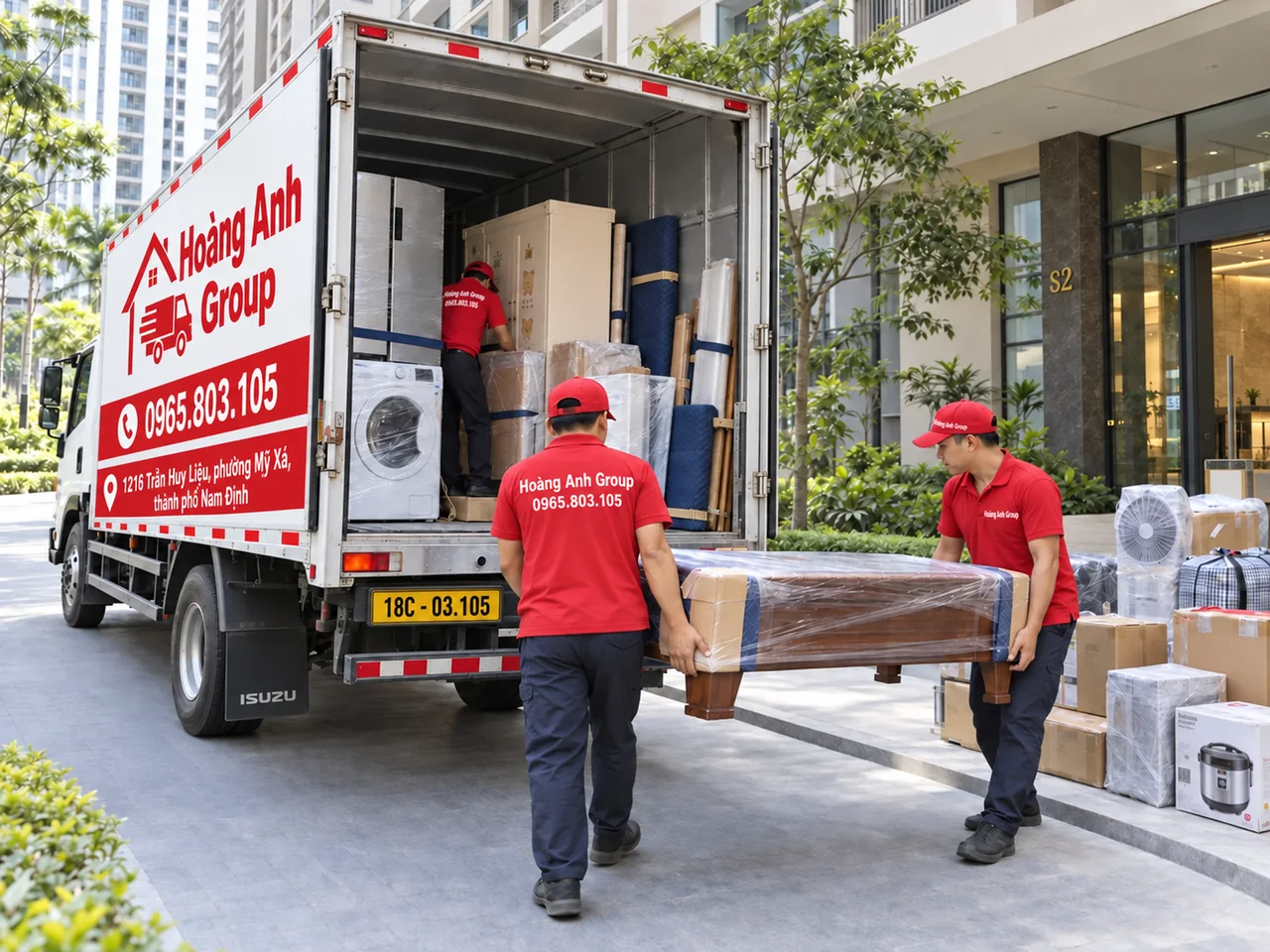Nhân viên áo đỏ Hoàng Anh Group cùng bê bàn gỗ đến cửa sau xe tải